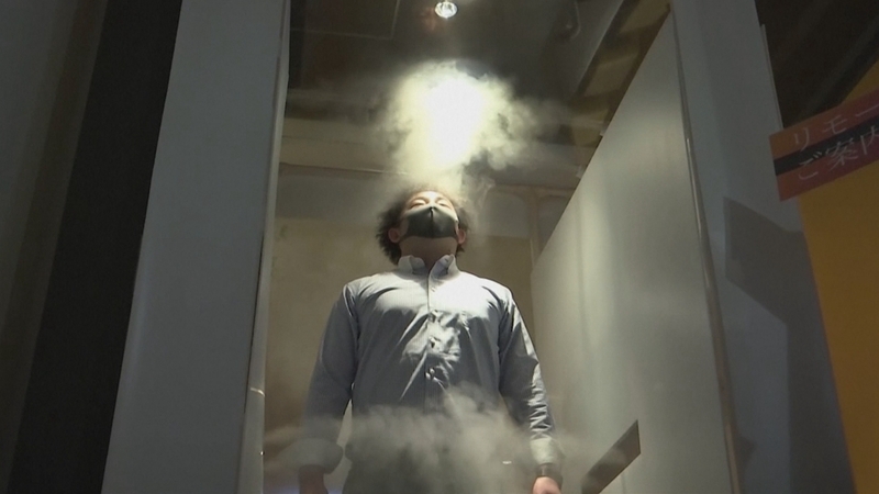 Customers step into a machine to be sprayed with a mist of chlorine-based disinfectant for 30 seconds