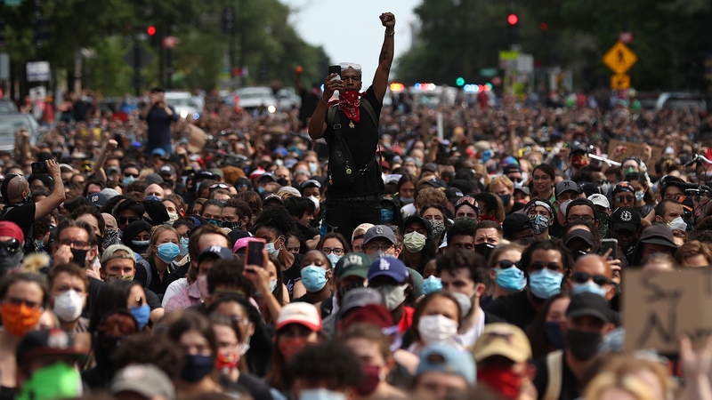 A man holds up his fist while hundreds of demonstrators march to protest against police brutality and the death of George Floyd in Washington, DC