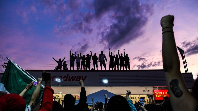 People raise their hands and shout slogans as they protest at a makeshift memorial in Minneapolis