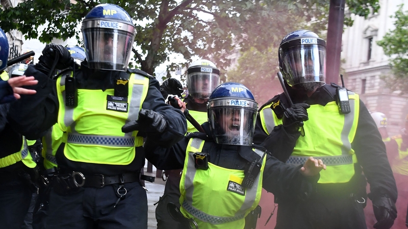 Police officers in riot gear shouting at protesters near Downing Street