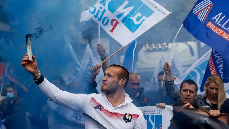 A demonstrator holds a flare during a protest of members of French police unions including Alliance Police Nationale on the Champs-Élysées