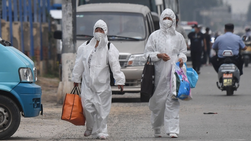 Two women wearing protective suits in Beijing, China after 11 residential estates were locked down