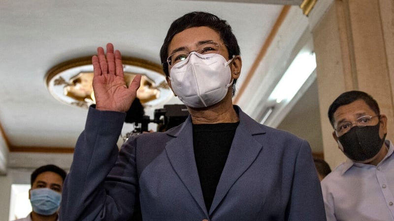 Maria Ressa waves to journalists following her conviction