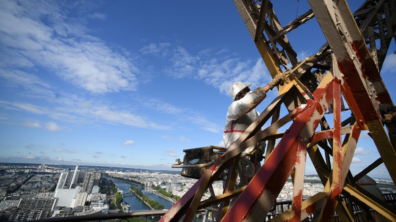 A man paints the Eiffel Tower as part of preparations for reopening
