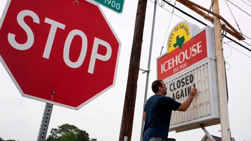 A bar owner changes the sign outside his bar to 'Closed Again' in Houston, Texas