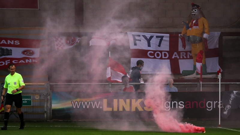 A grinning dummy looks on as a flare somehow made its on to the pitch despite no paying fans being present