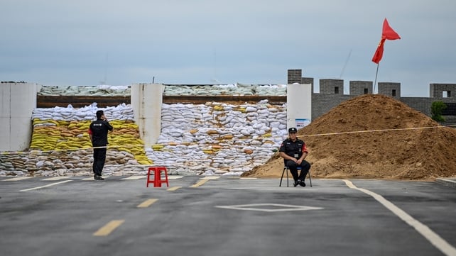 Security members are seen next to a wall covered with sandbags in Poyang Lake