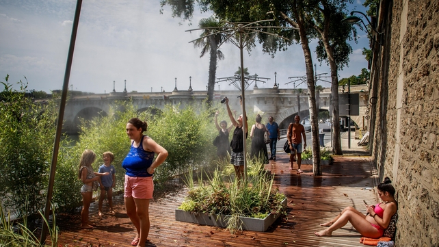 People enjoy spraying water as a heatwave rolls over Paris, where temperatures hit 39C