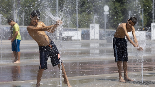 Children cool off with water-jets in the fountain at the Place des Nations in Geneva
