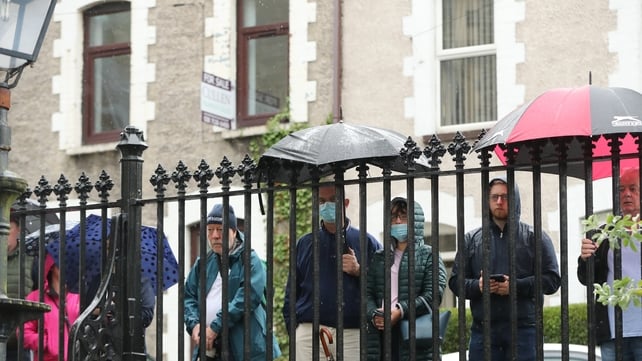 People stand outside St Eugene's Cathedral during the funeral of John Hume