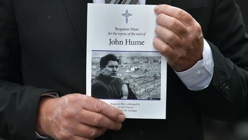 A mourner holds an order of service as the funeral takes place