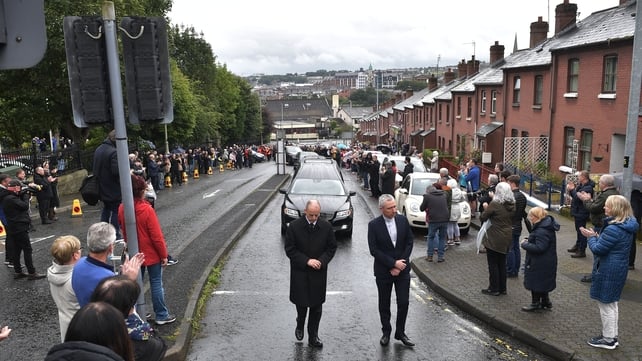 Local well-wishers applaud the cortege as it drives through Derry