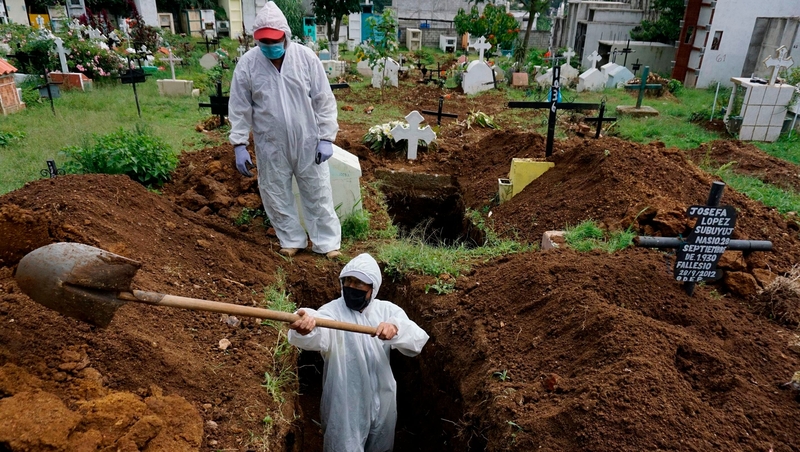 A gravedigger wearing a biosafety suit digs a grave to bury the coffin of a Covid-19 victim near Guatemala City