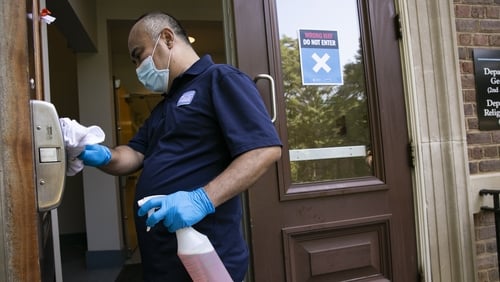 Ko Soe, a member of the university custodial staff, disinfects a door handle at a classroom building on the University of North Carolina campus