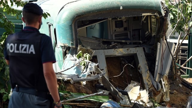 A policeman inspects the damage to the derailed carriage