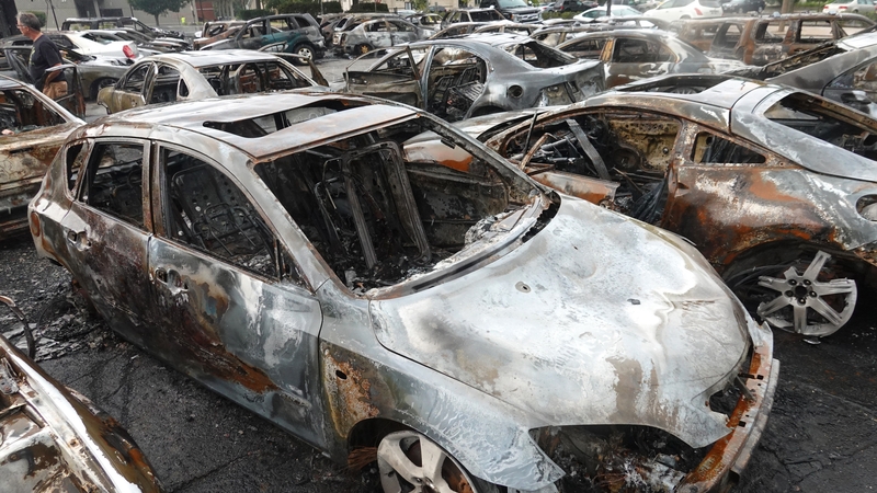 Cars sit in a used car garage that was torched during last night's unrest in Kenosha, Wisconsin