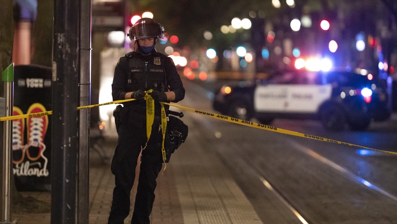 A police man ties a police line near the scene of the fatal shooting in Portland