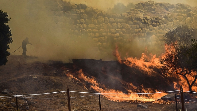 Flames licked the ruins as the bushfire spread, the southern Peloponnese region's fire brigade confirmed