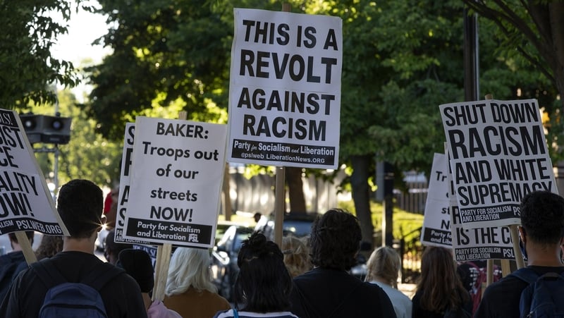 People hold placards during a demonstration and vigil in support of victims of police brutality in Boston