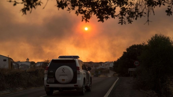 A Civil Guard patrol car in El Buitron in Huelva as smoke billows from a wildfire