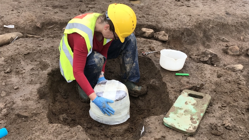 Specialist archaeological conservator Susannah Kelly wraps the urn in bandages to protect it for its removal
