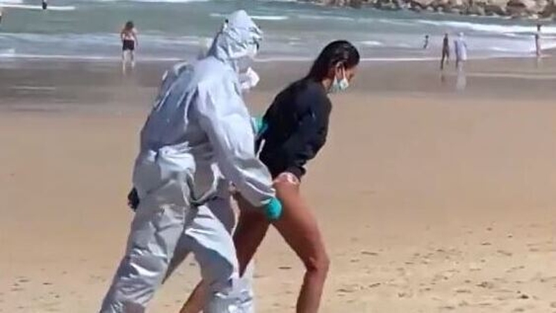 Gloved officers in white hazmat suits marched the handcuffed woman off the beach in the northern city of San Sebastian (Pic: @JavierSanz)