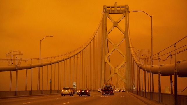 Cars drive along the San Francisco Bay Bridge under an orange smoke filled sky in San Francisco San Francisco