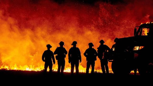 Butte County firefighters watch as flames quickly spread across a road at the Bear fire in Oroville, California
