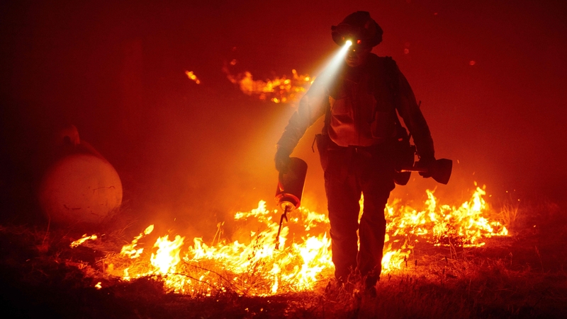 Firefighters cut defensive lines and light backfires to protect structures behind a CalFire fire station during the Bear fire, part of the North Lightning Complex fires in the Berry Creek area of Butte County