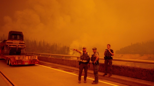 Law enforcement and fire personnel wait on the Enterprise Bridge to enter an area encroached by fire in Butte County