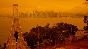 Jose Castillo has his photo taken with the Bay Bridge and the San Francisco skyline in the background by his friend Laito Miyake, both of San Francisco, as smoky skies from the northern California wildfires casts an orange and yellow color in San Francisc
