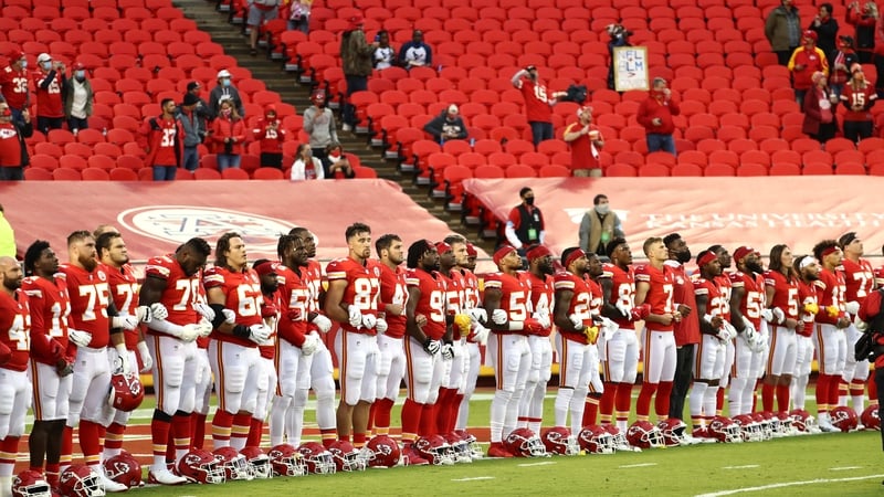 Members of the Kansas City Chiefs link arms before a sparse crowd at Arrowhead Stadium