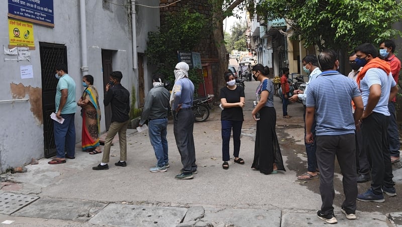 People stand in line as they wait for their coronavirus test in New Delhi, India