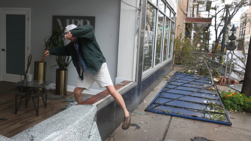 A business owner climbs through the smashed front window and debris of his store in Mobile, Alabama