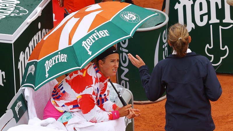 Azarenka speaks to an official from under an umbrella
