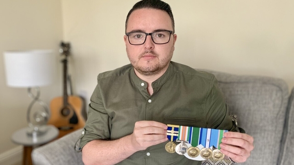 Ciaran O'Neill holds up army medals that were presented to him by his father after his coronavirus battle
