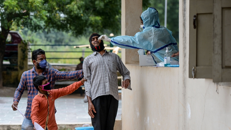 People assist a man as he undergoes a Covid-19 test in Hyderabad, India