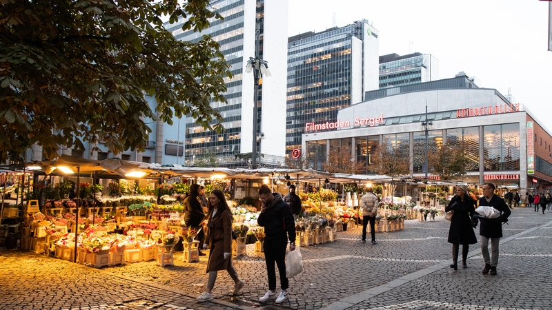 People walk past flower stalls at Hotorget square in central Stockholm