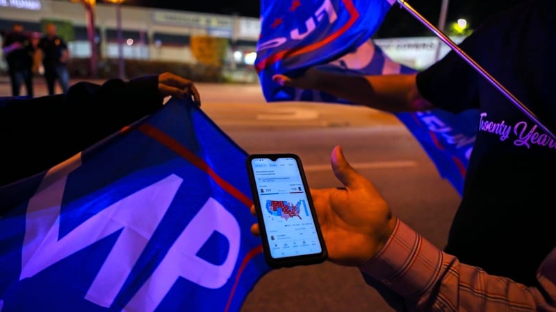 Trump supporters check in on developments during a rally in Miami, Florida