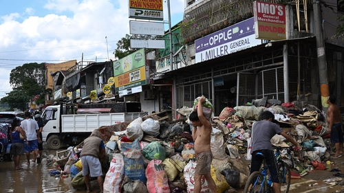 Motorists travel past trash and debris swept up on a bridge in Manila after Typhoon Vamco hit