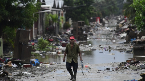 A man walks trough rubbish and floodwaters at Barrio San Juan in La Lima, Honduras, today