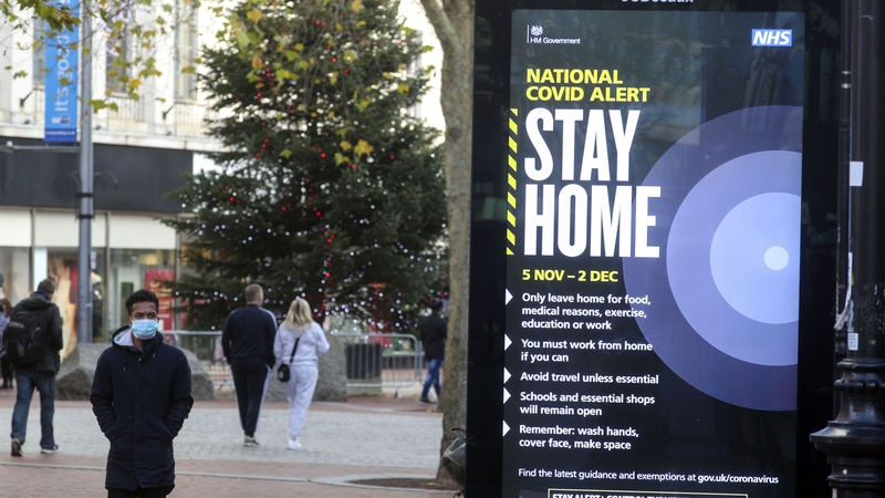 A shopper walks past a government advert on Covid-19 in Reading, England