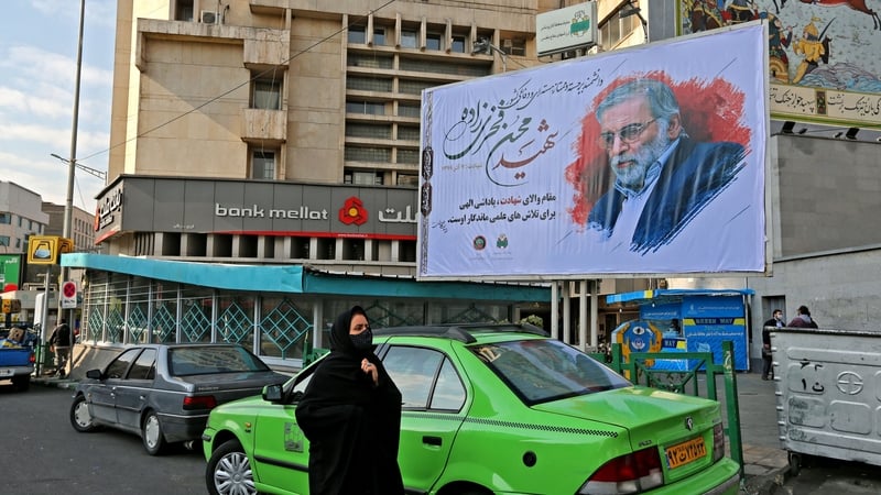 A woman walks past a billboard showing Mohsen Fakhrizadeh in Tehran