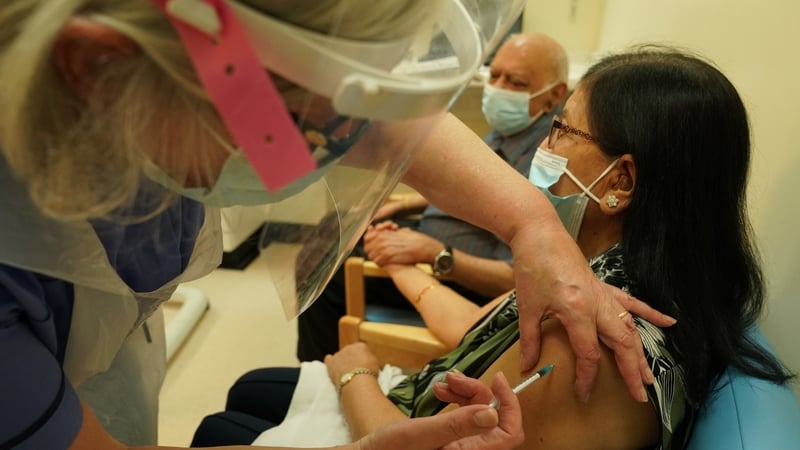 A woman receives one of the first Covid-19 vaccinations in the UK