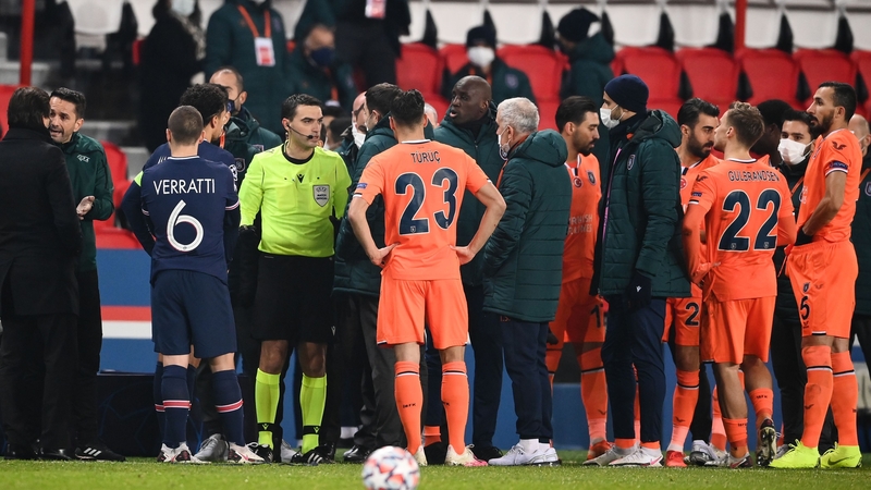 Romanian referee Ovidiu Hategan (in yellow) talks to Istanbul Basaksehir's staff members before they walk off