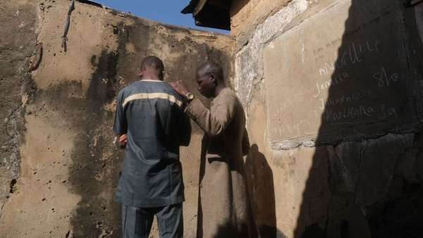 A boy who escaped from the gunmen stands with his father in their home in Kankara town
