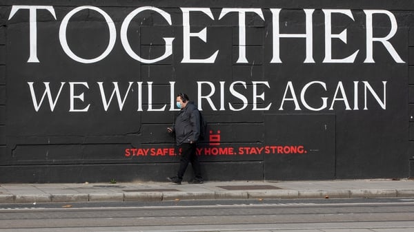 A man wearing a face mask walks past a mural in Dublin in October