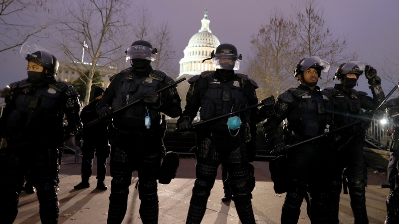 Police officers in riot gear line up as protesters gather on the US Capitol Building