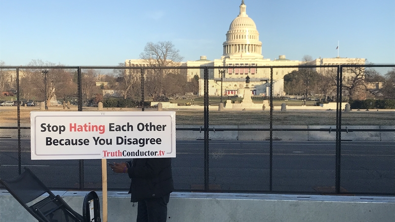 A man holds a sign urging unity near the US Capitol