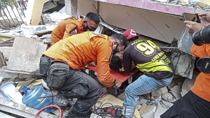 A survivor is pulled out of the ruin of a collapsed building following a 6.2 magnitude earthquake in Mamuju, West Sulawesi, Indonesia